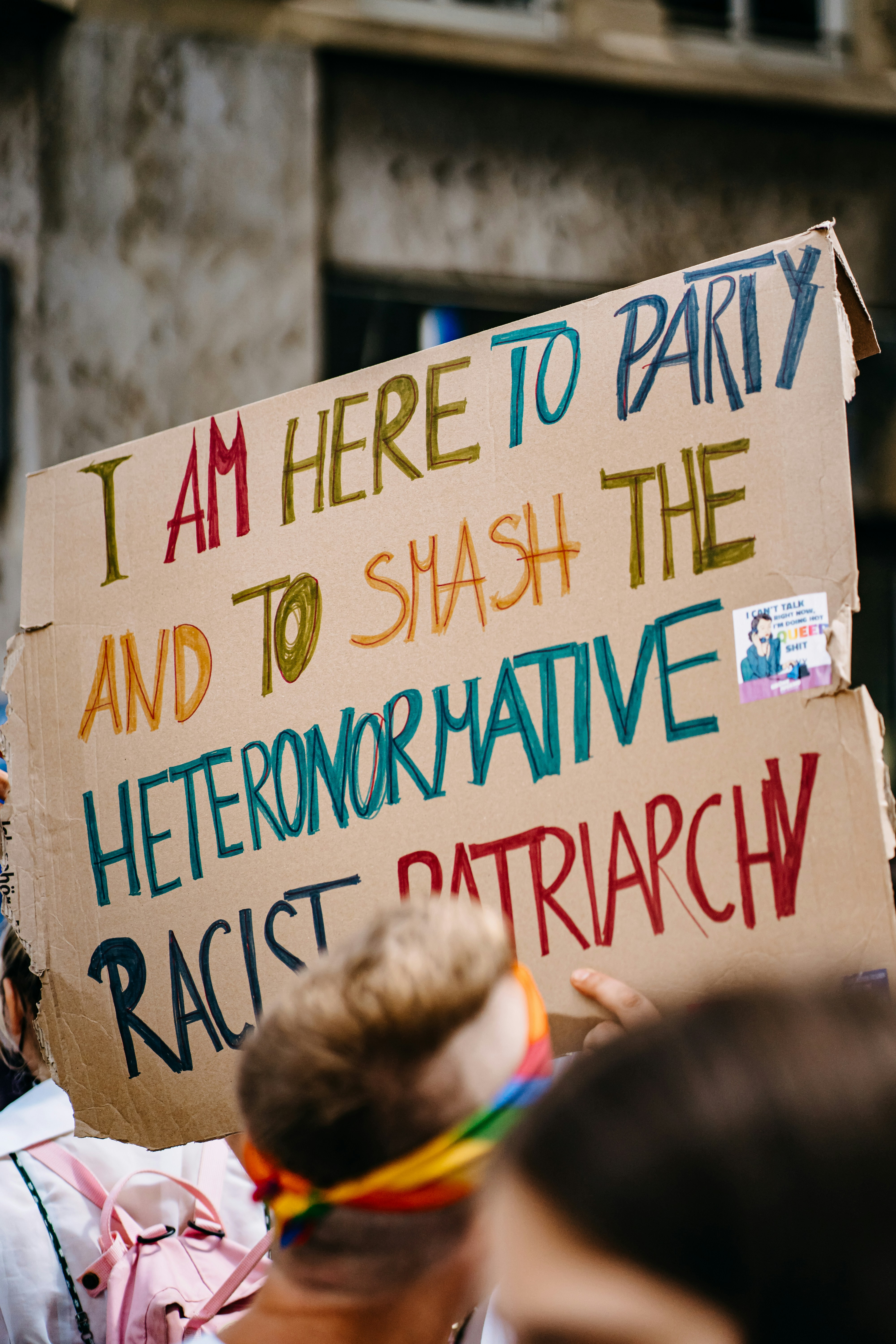 cardboard protest sign that with handwritten multicolor words that read: I am here to party and to smash the heteronormative racist patriarch